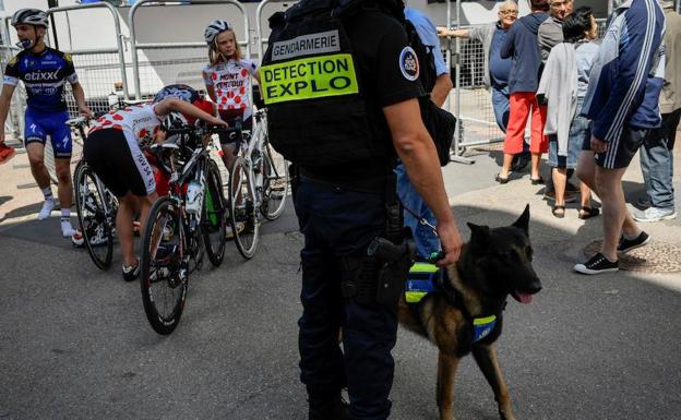 Un policía, acompañado de un perro detector de explosivos, vigila durante la tercera etapa. /Jeff Pachoud (Afp)
