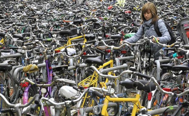 Una mujer deja su bicicleta en un aparcamiento público./Reuters