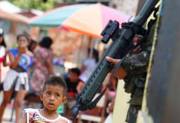 Un niño indígena observa el arma de un soldado brasileño desplegado en las maniobras militares en Tabatinga. :: reuters/