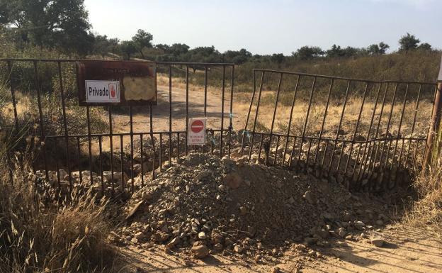 Camino cortado con una cancela y una zanja para impedir el paso./