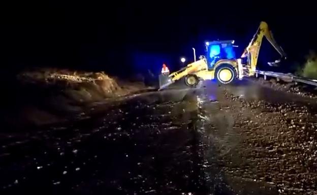 Maquinaria de conservación limpiando una carretera golpeada por la lluvia.