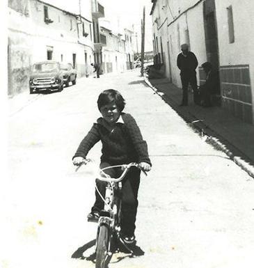 El niño Diego José Rubio pasea un tramo de la calle Almírez montado en su bicicleta a finales de los años 70. Puede verse aún el desaparecido Pozo del Cura. Cortesía Familia Rubio Chaves./