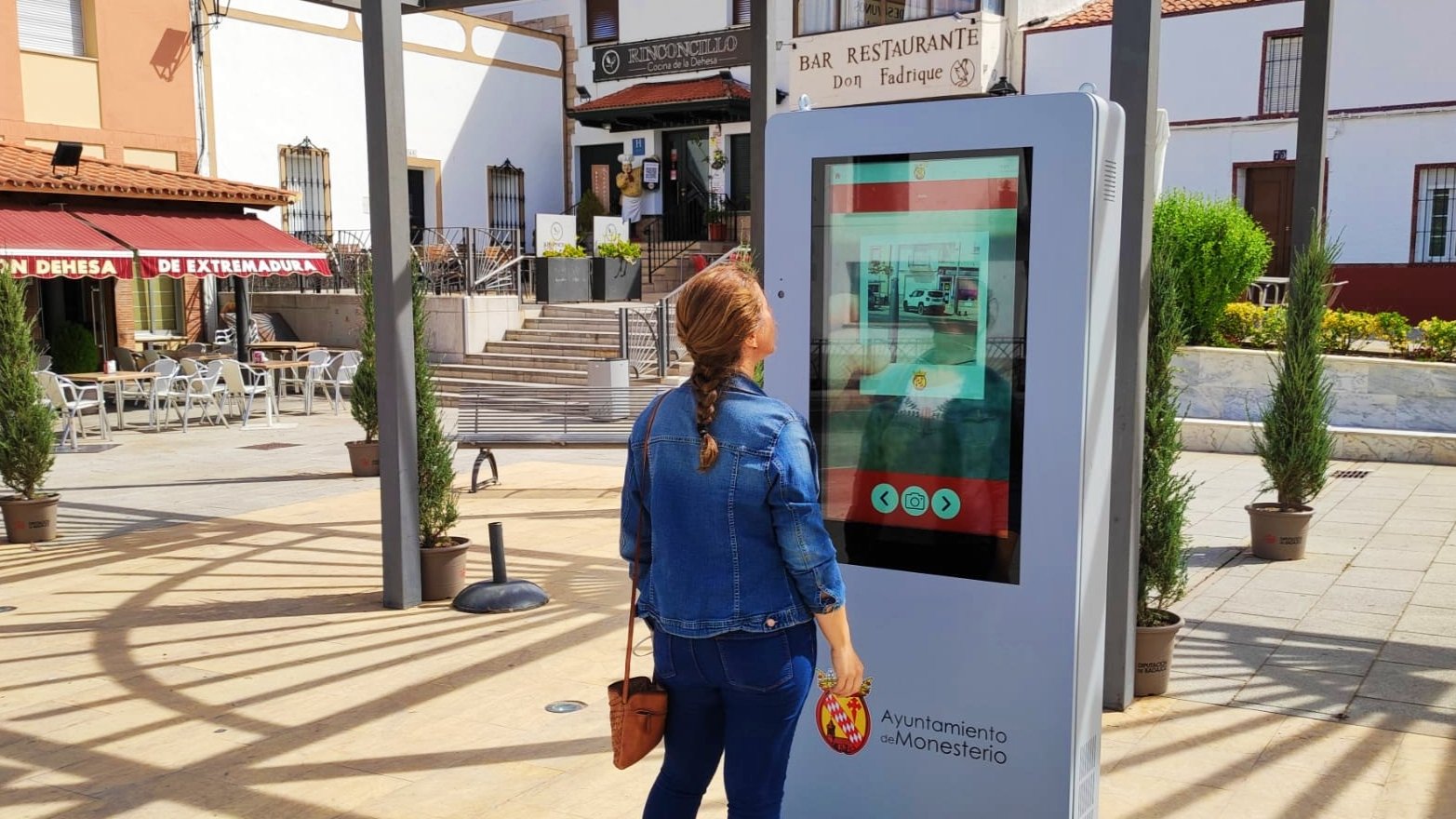 Una mujer consulta el tótem digital instalado en la Plaza de Triana de Monesterio /AYUNTAMIENTO DE MONESTERIO