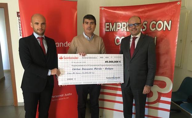 Representantes del Banco Santander entregando el cheque al representante de Cáritas Mérida-Badajoz.