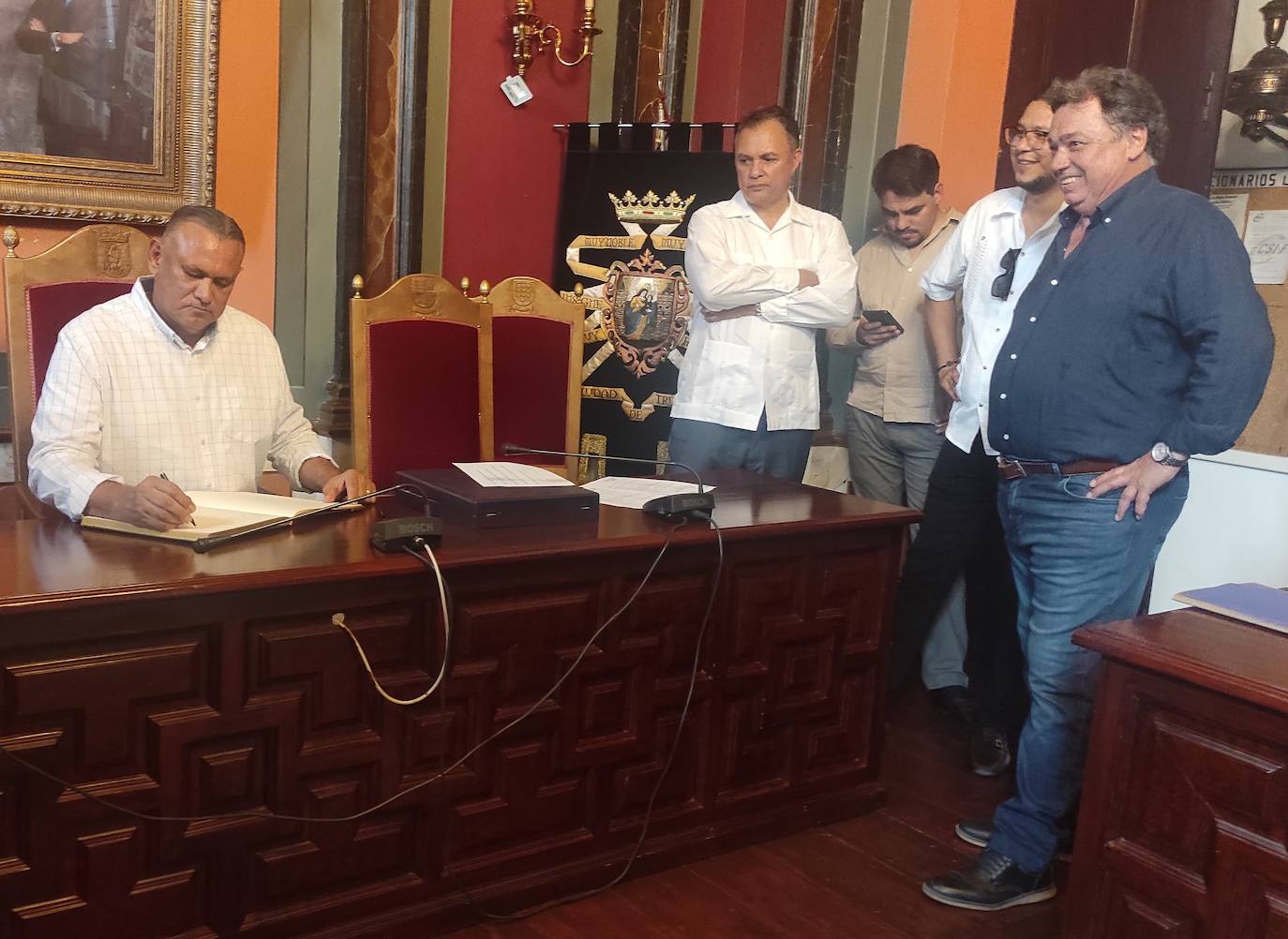 El alcalde de Trujillo de Honduras firmando en el libro de honor de la ciudad, ante la atenta mirada del alcalde anfritrión 