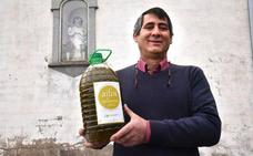 Juan M. Martín, con una botella de su aceite ante la imagen de Dios Padre./David Palma