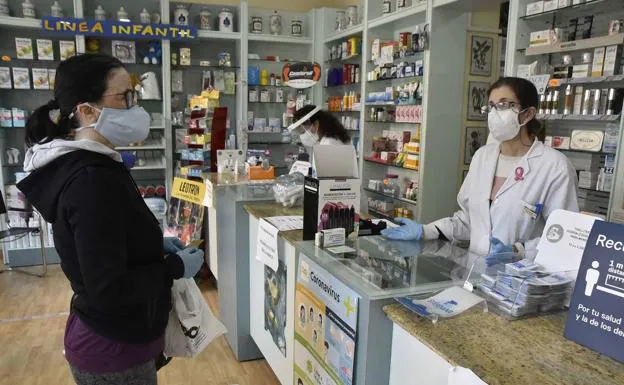 Imagen de archivo de una farmacia de Badajoz atendiendo a una clienta a distancia y con mascarilla. /Hoy