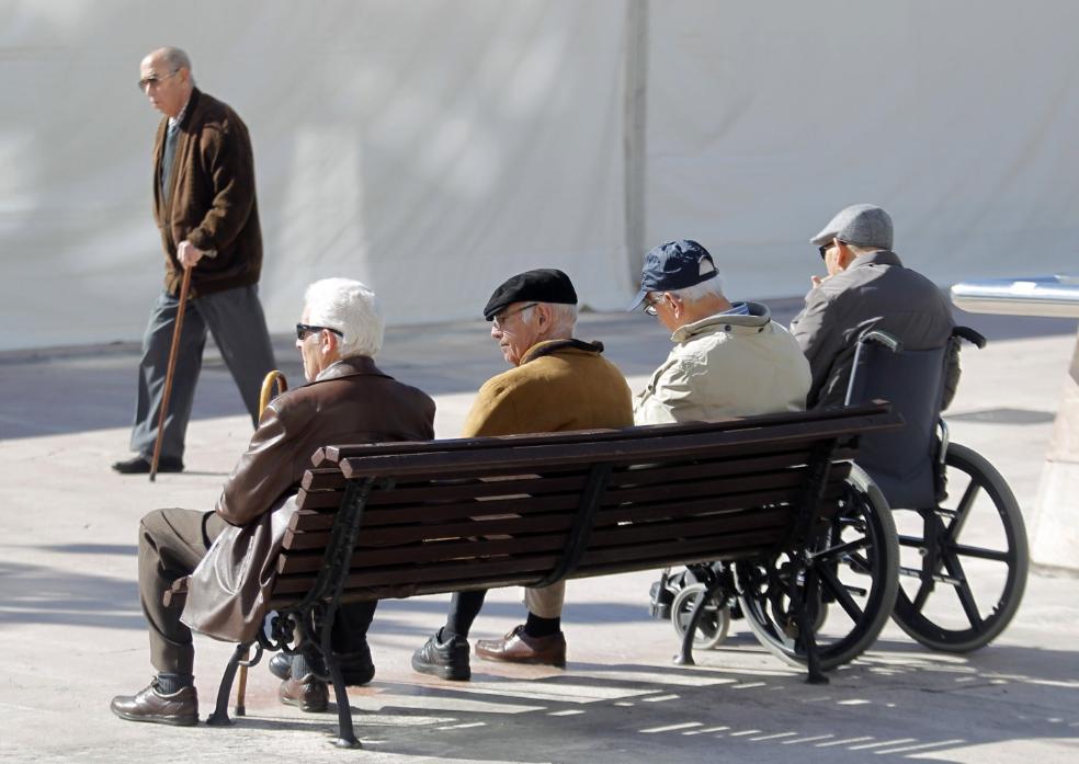 Personas mayores toman el sol en el banco de un parque. / HOY