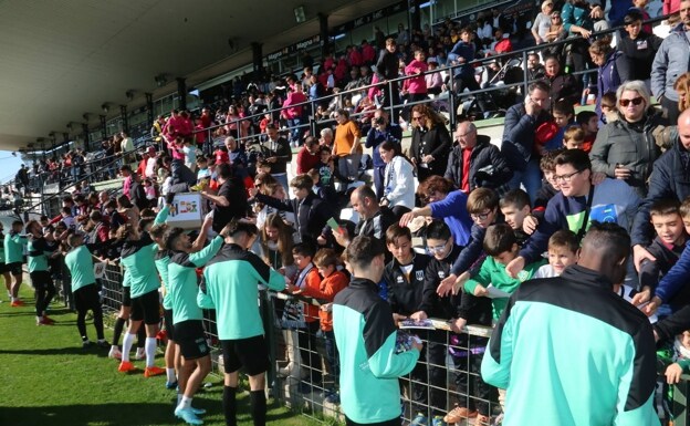 Los jugadores del Mérida firmando y regalando golosinas a los aficionados más pequeños. /J. M. Romero